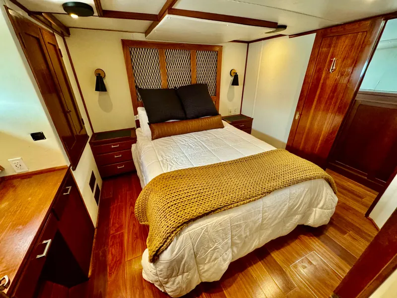 Slide: The Image of Luxurious bedroom interior of a 1976 Nordlund 60 Motoryacht with wood accents and cozy bedding. - 14
