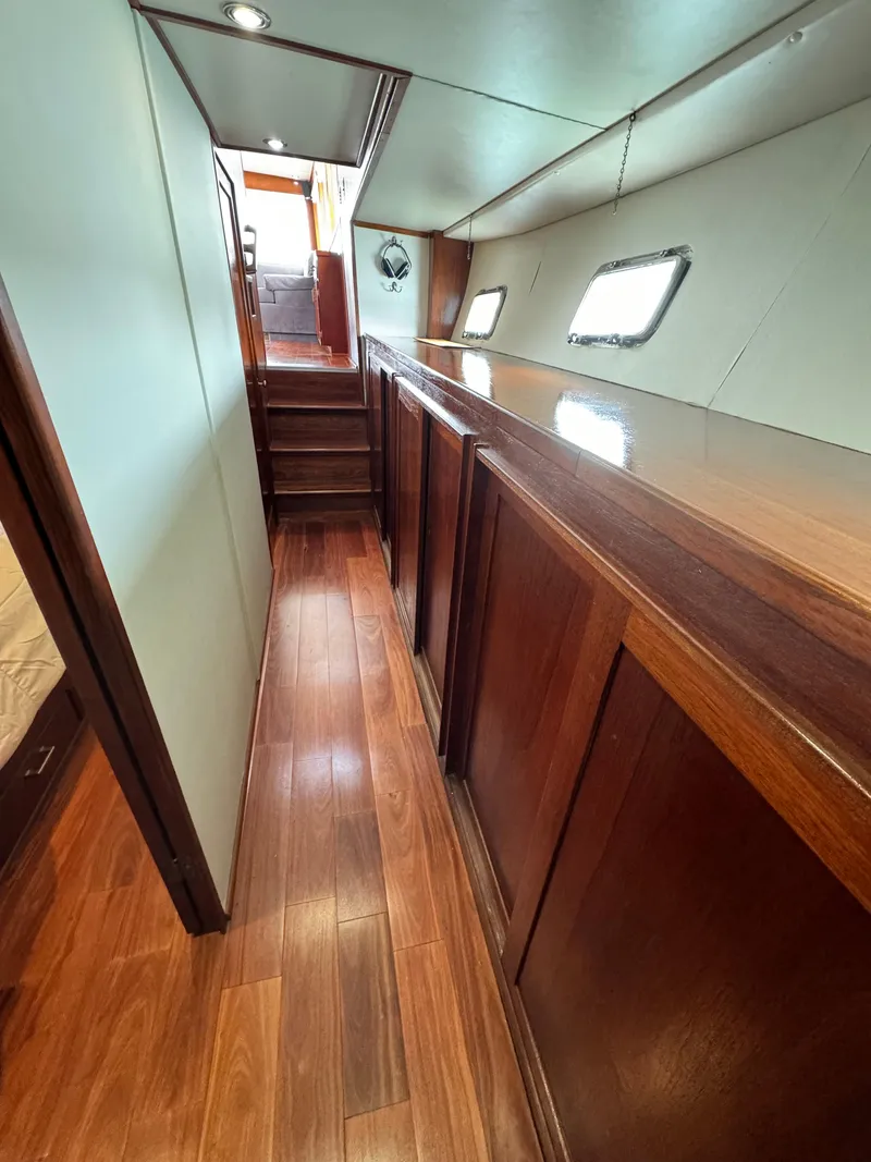 Slide: The Image of 1976 Nordlund 60 Motoryacht interior with wooden flooring and cabinetry, featuring porthole windows. - 18