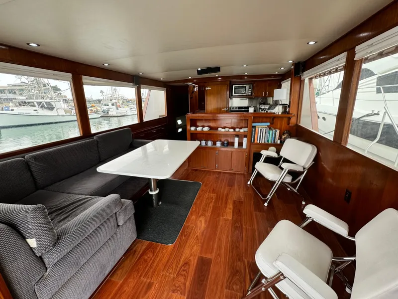 Slide: The Image of Interior of 1976 Nordlund 60 Motoryacht with wood flooring, seating, and kitchenette. - 2