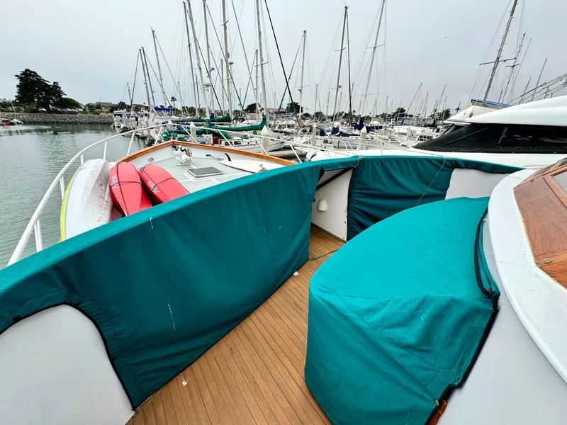 Slide: The Image of 1976 Nordlund 60 Motoryacht deck with teal covers and docked sailboats in background. - 38