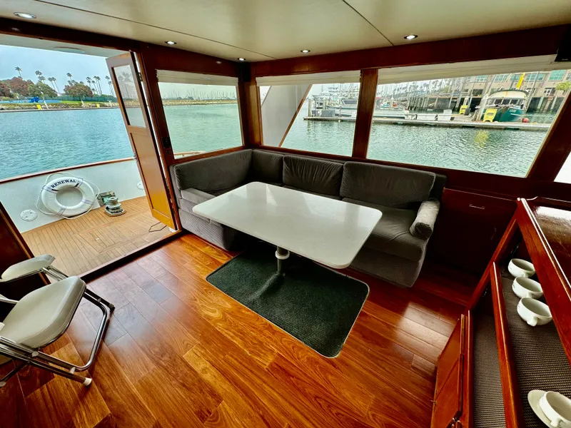 Slide: The Image of 1976 Nordlund 60 Motoryacht interior with wood flooring, dining area, and waterfront view. - 4