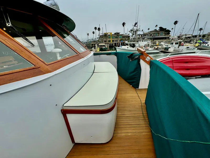 Slide: The Image of 1976 Nordlund 60 Motoryacht with wooden deck and cushioned seating in a marina setting. - 40