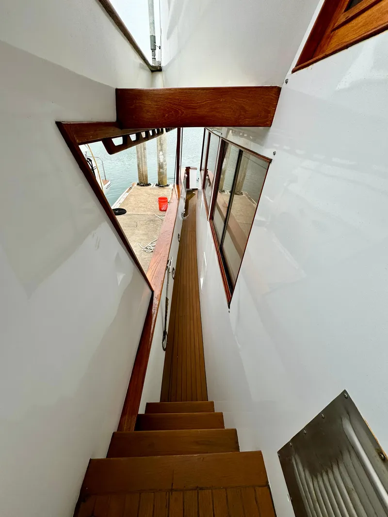 Slide: The Image of Stairway on 1976 Nordlund 60 Motoryacht with wooden accents and dockside view. - 46