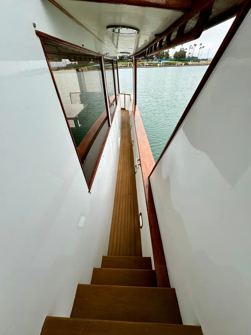 Slide: The Image of 1976 Nordlund 60 Motoryacht side deck with wooden steps and railing, overlooking calm water. - 47