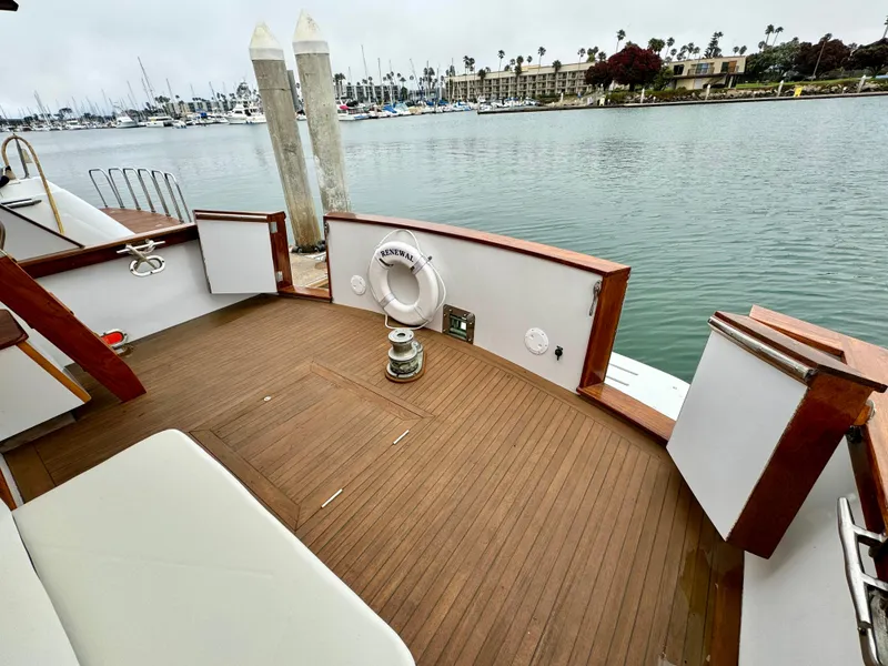 Slide: The Image of 1976 Nordlund 60 Motoryacht deck with wooden flooring, docked by calm waters. - 48