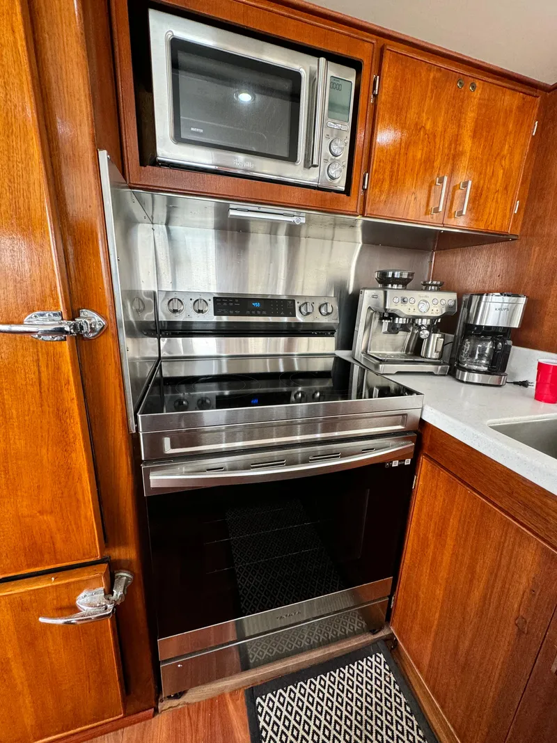 Slide: The Image of Kitchen area in a 1976 Nordlund 60 Motoryacht with modern appliances and wooden cabinetry. - 7
