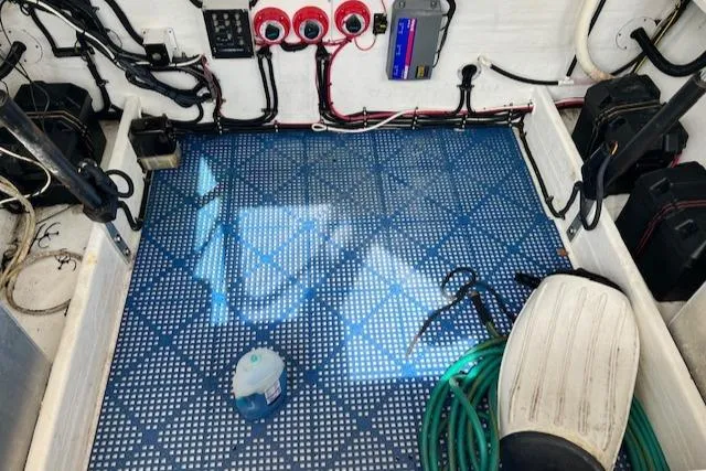 Slide: The Image of 2005 Contender 35 Side Console boat interior with wiring, equipment, and blue patterned flooring. - 12