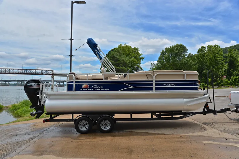 Slide: The Image of 2018 Sun Tracker Party Barge 20 DLX pontoon boat on trailer by a river. - 15