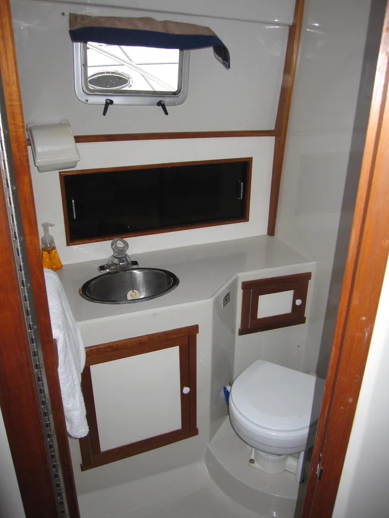 Slide: The Image of 1990 Blue Seas 31 Hardtop Cruiser bathroom with sink, toilet, and storage cabinets. - 30