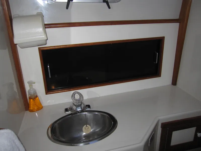 Slide: The Image of 1990 Blue Seas 31 Hardtop Cruiser bathroom sink with window and soap dispenser. - 31