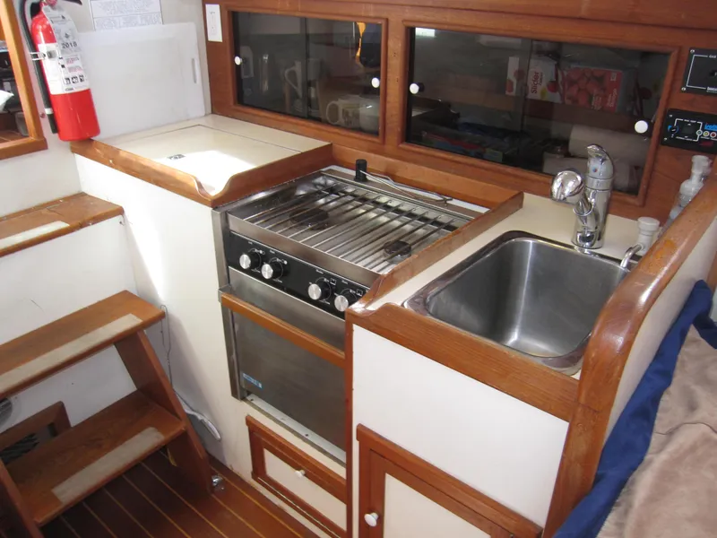 Slide: The Image of Compact kitchen area in 1990 Blue Seas 31 Hardtop Cruiser with stove, sink, and wooden cabinetry. - 9