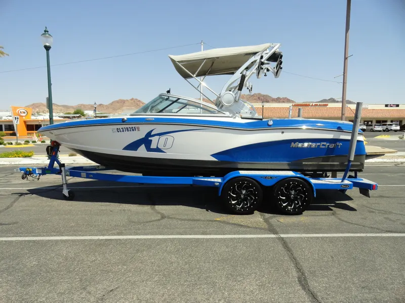 Slide: The Image of 2013 MasterCraft X-10 boat on a blue trailer in a parking lot. - 1