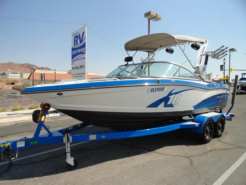Slide: The Image of 2013 MasterCraft X-10 boat on a blue trailer in a parking lot. - 2