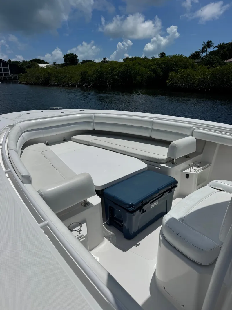 Slide: The Image of The image shows the bow of a 2015 Southport 33 boat with white seating and a blue cooler. - 16