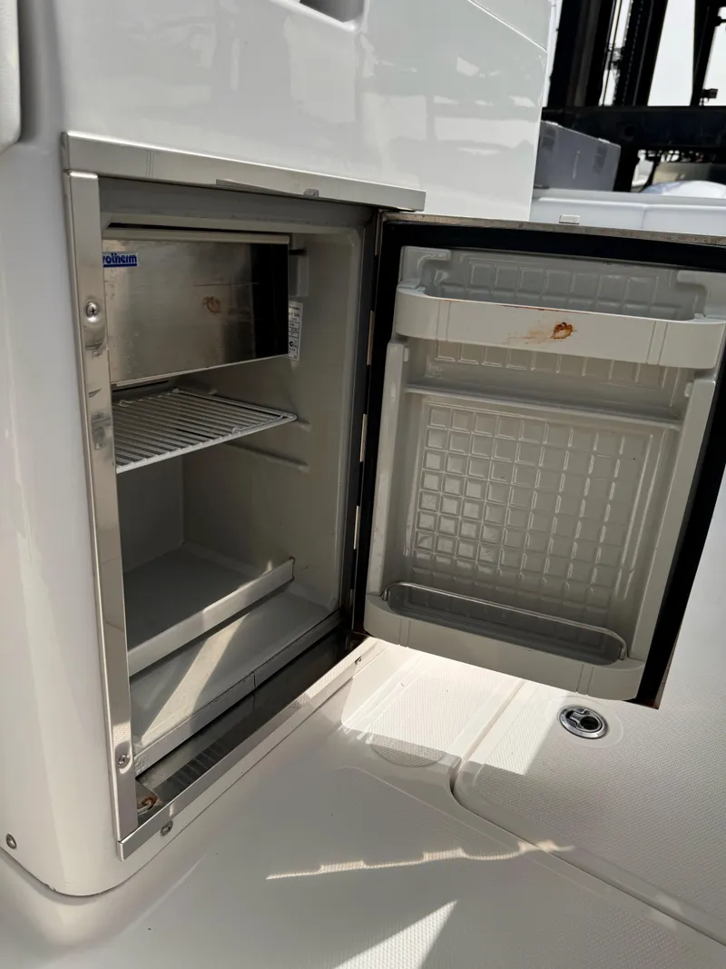Slide: The Image of Open mini fridge on a 2015 Southport 33 boat, showing interior shelves. - 8
