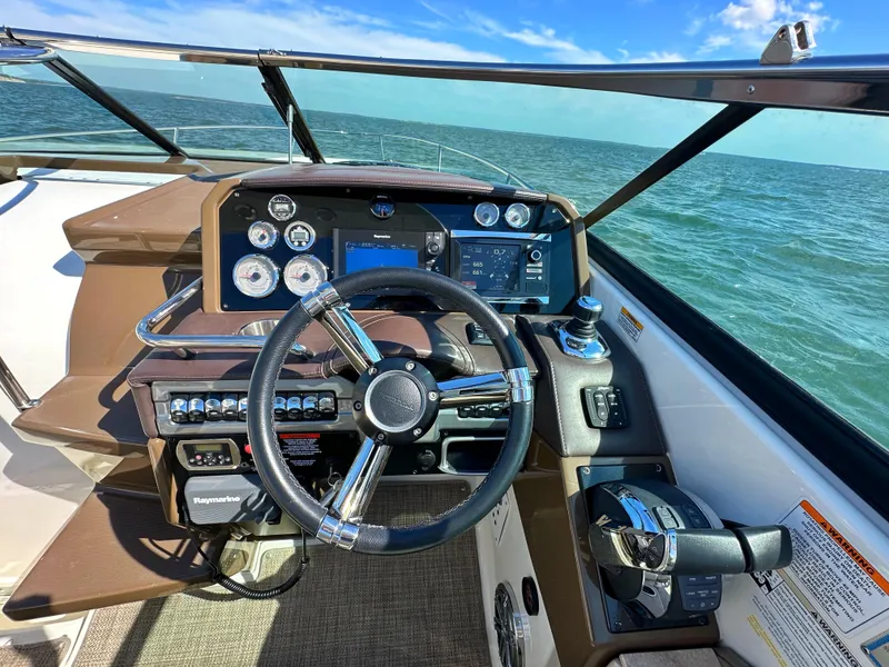 Slide: The Image of 2015 Formula 310 Sun Sport boat dashboard with steering wheel and control panel on open water. - 22