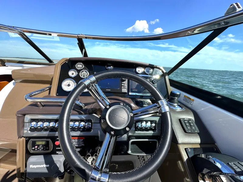 Slide: The Image of 2015 Formula 310 Sun Sport boat dashboard with steering wheel and ocean view. - 23