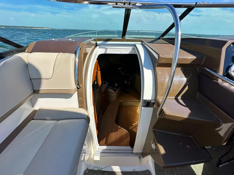 Slide: The Image of 2015 Formula 310 Sun Sport boat interior with open cabin door, beige seating, and ocean view. - 25
