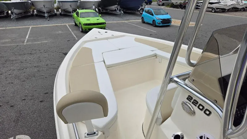 Slide: The Image of 2025 Bulls Bay 2200 boat interior with seating and console, parked in a lot with cars and boats. - 11