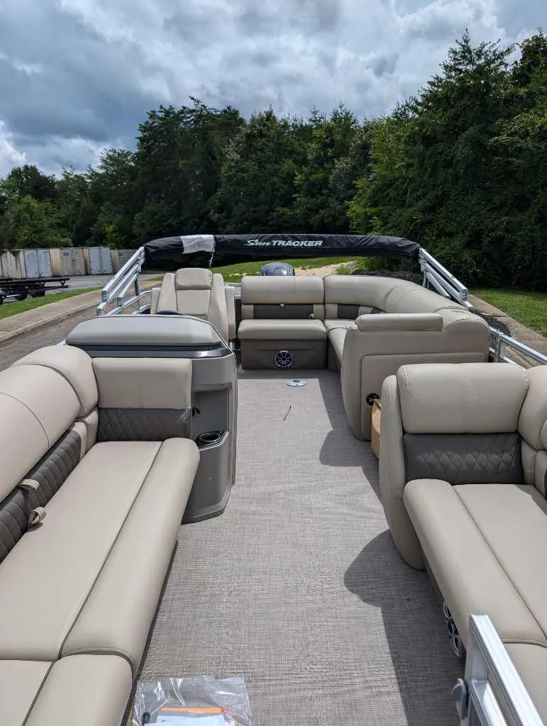 Slide: The Image of 2024 Sun Tracker Party Barge 20 DLX pontoon boat with spacious seating and lush greenery background. - 2