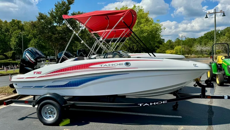 Slide: The Image of 2024 Tahoe T16 boat with red canopy on trailer, parked outdoors. - 0