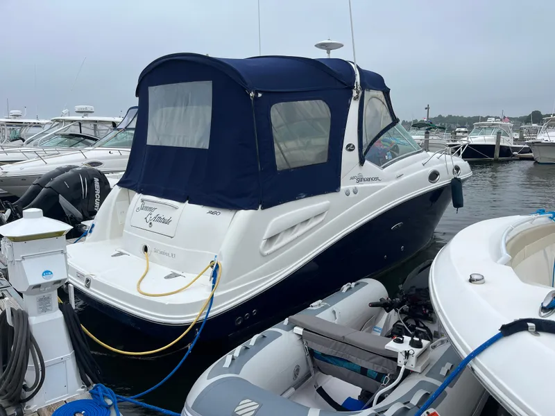 Slide: The Image of 2006 Sea Ray 260 Sundancer docked at marina with blue canvas cover. - 1