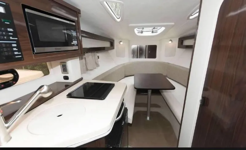 Slide: The Image of Interior of 2018 Sea Ray Sundancer 260, featuring a compact kitchen and cozy seating area. - 27