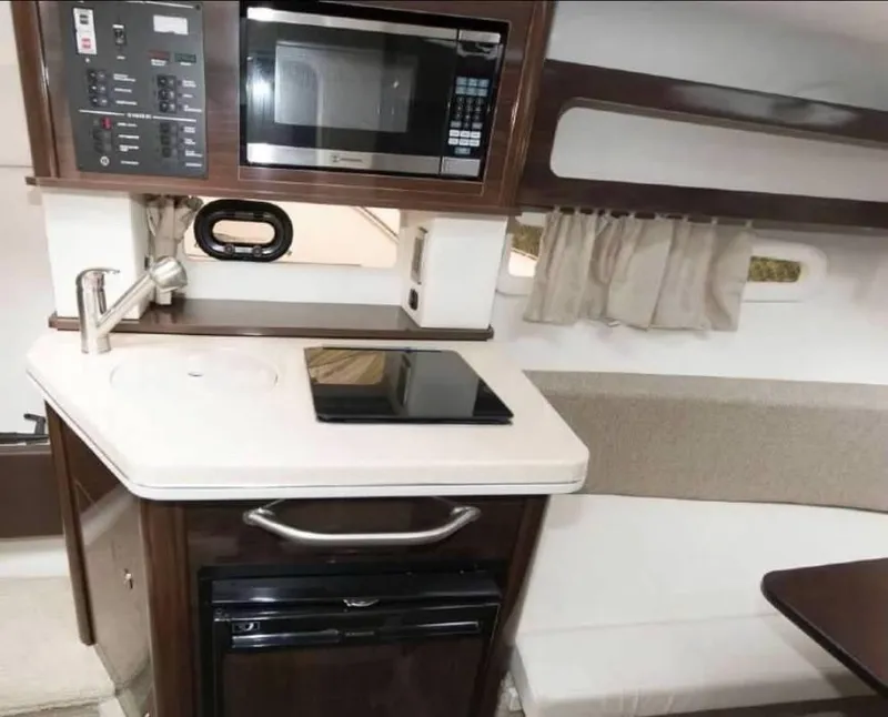 Slide: The Image of 2018 Sea Ray Sundancer 260 galley with microwave, stovetop, and compact fridge. - 28