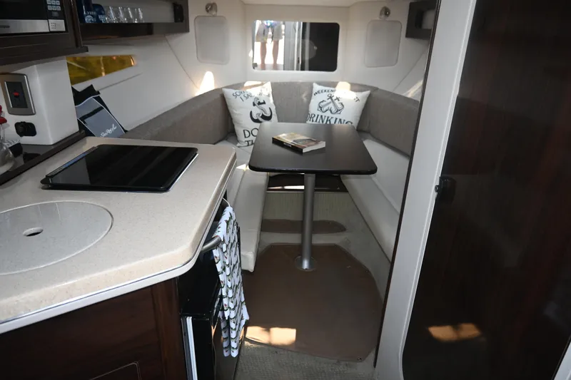 Slide: The Image of 2018 Sea Ray Sundancer 260 cabin interior with seating, table, and kitchenette. - 31