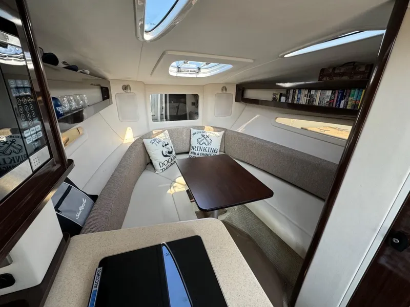 Slide: The Image of Interior of 2018 Sea Ray Sundancer 260, featuring cozy seating and a wooden table. - 32