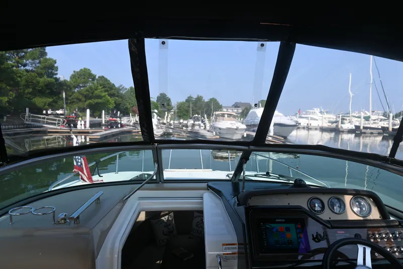Slide: The Image of 2018 Sea Ray Sundancer 260 cockpit view at marina with boats and trees. - 6
