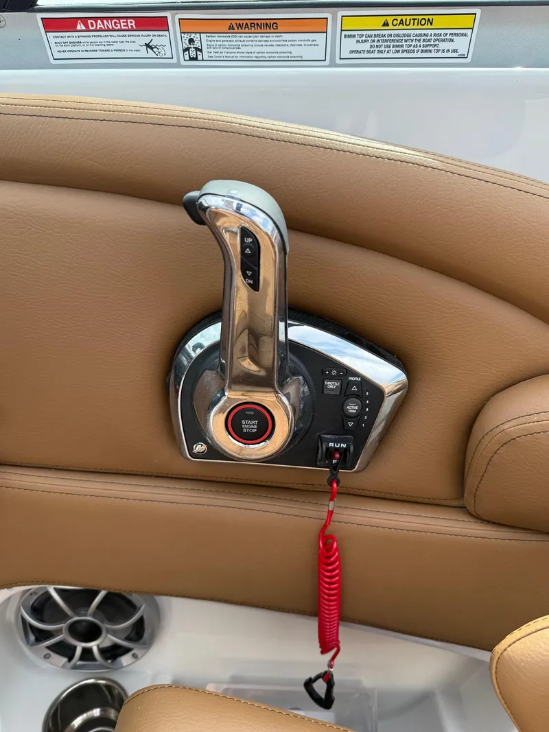 Slide: The Image of 2025 Crownline 290 SS throttle control with beige leather interior and safety warnings. - 12