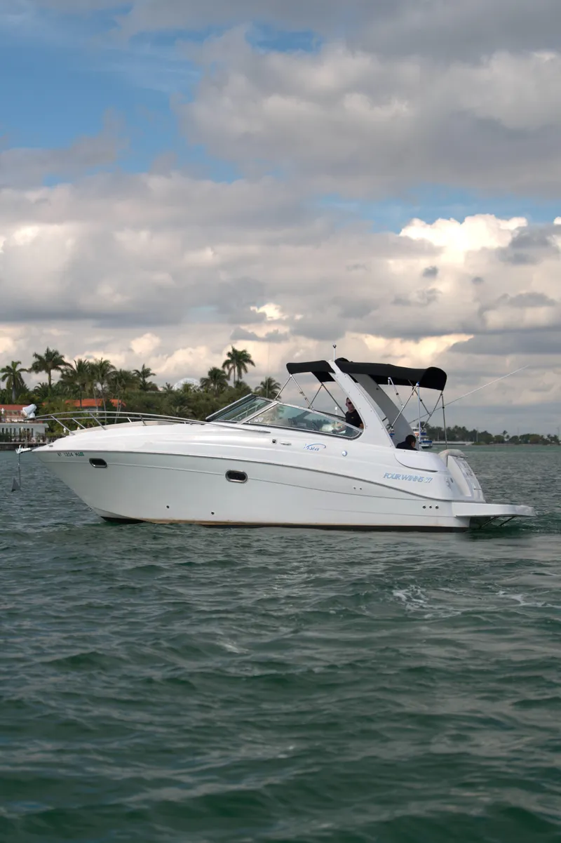 Slide: The Image of 2004 Four Winns Vista boat cruising on a lake under a cloudy sky. - 0