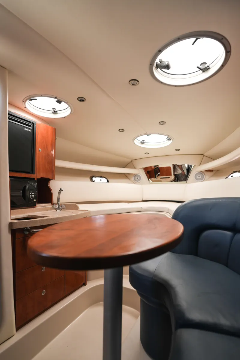 Slide: The Image of Interior of 2004 Four Winns Vista boat with wooden table and blue seating. - 12