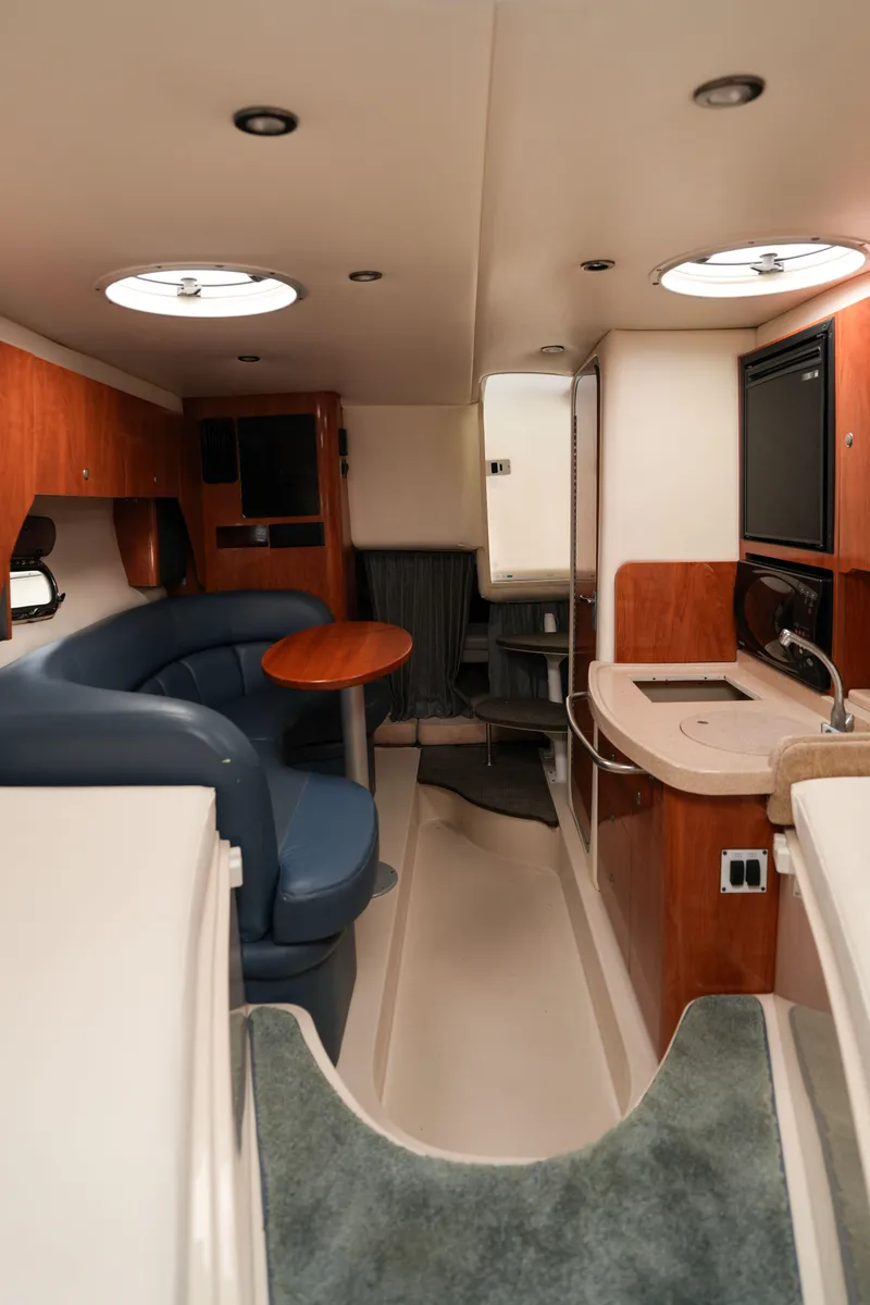 Slide: The Image of 2004 Four Winns Vista boat interior with seating, table, and kitchenette. - 13