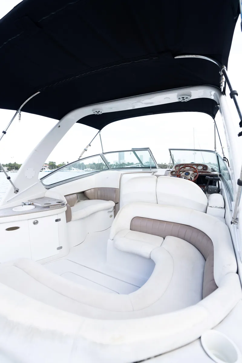 Slide: The Image of 2004 Four Winns Vista boat interior with white and beige seating under a black canopy. - 16