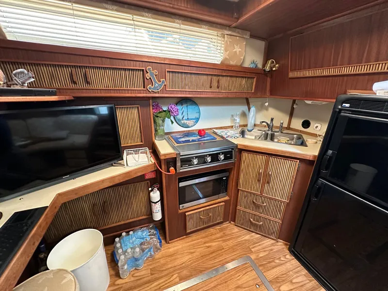 Slide: The Image of 1986 Sea Ray 390 Express Cruiser kitchen with stove, sink, and refrigerator. - 18