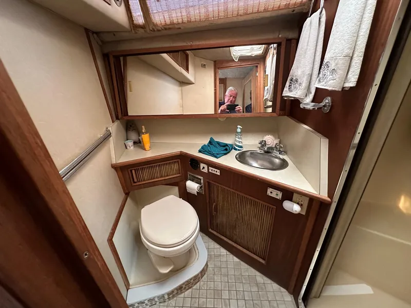 Slide: The Image of 1986 Sea Ray 390 Express Cruiser bathroom with sink, toilet, and mirror. - 22
