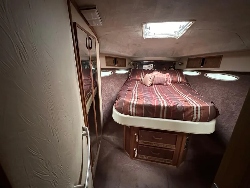 Slide: The Image of 1986 Sea Ray 390 Express Cruiser cabin with bed, skylight, and storage. - 24