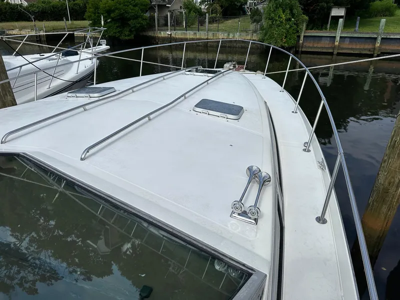 Slide: The Image of 1986 Sea Ray 390 Express Cruiser docked, showing bow deck and railings. - 3
