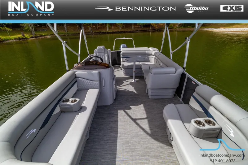 Slide: The Image of 2023 Bennington 20 SLM pontoon boat interior with spacious seating and cup holders on a lake. - 18