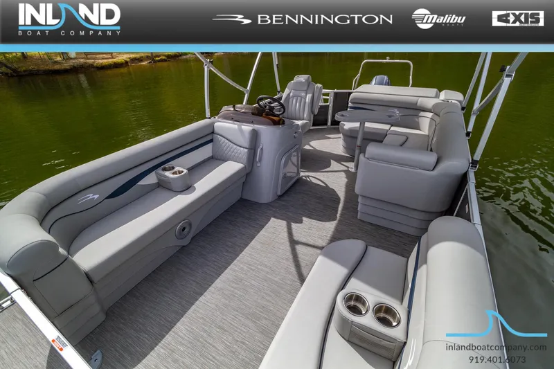Slide: The Image of 2023 Bennington 20 SLM pontoon boat interior with gray seating and cup holders on a lake. - 19