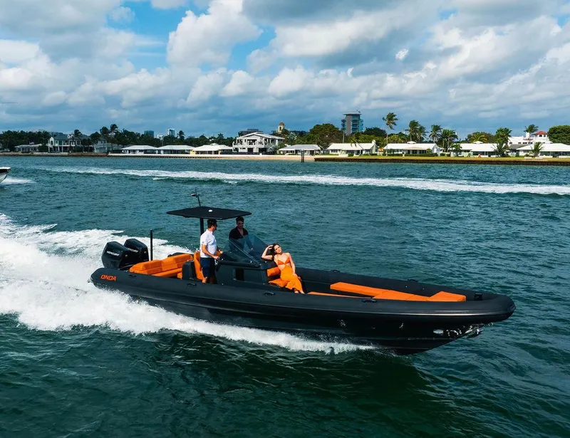 Slide: The Image of 2024 Onda Magna boat cruising on water with passengers, scenic coastal background. - 3