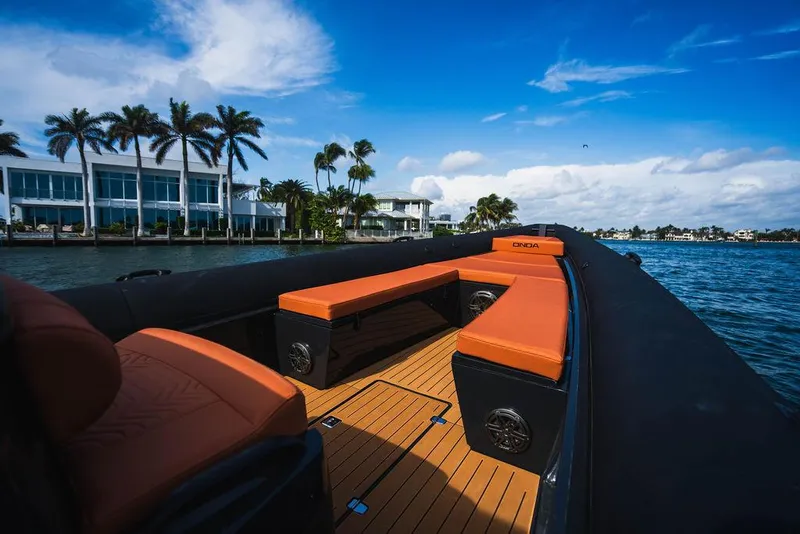 Slide: The Image of 2024 Onda Magna boat with orange seating, cruising near waterfront homes and palm trees. - 4