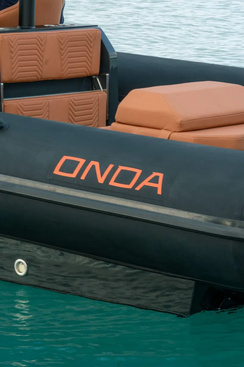 Slide: The Image of 2024 Onda Magna boat with orange seating and logo on black hull. - 6