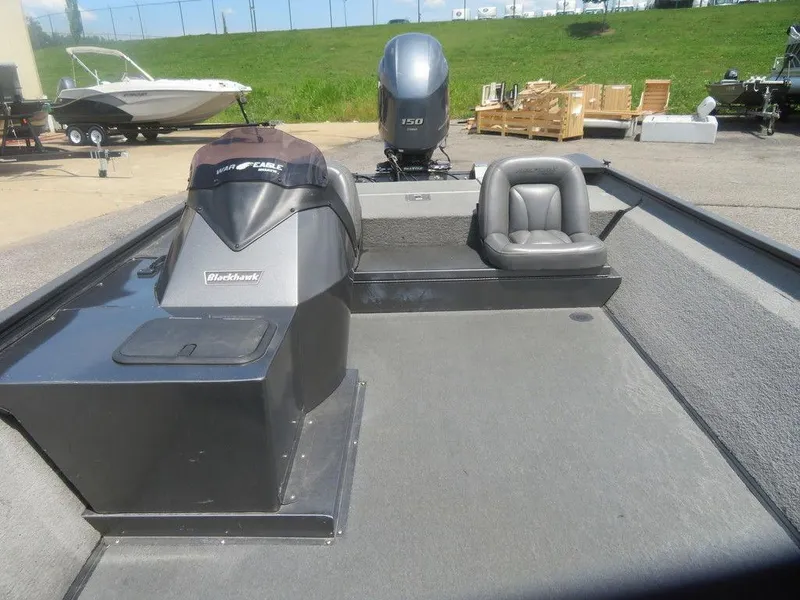 Slide: The Image of 2019 War Eagle 2170 boat interior with seating and motor, parked outdoors. - 5
