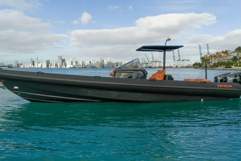 Slide: The Image of 2024 Onda Magna boat on turquoise water with city skyline in the background. - 1