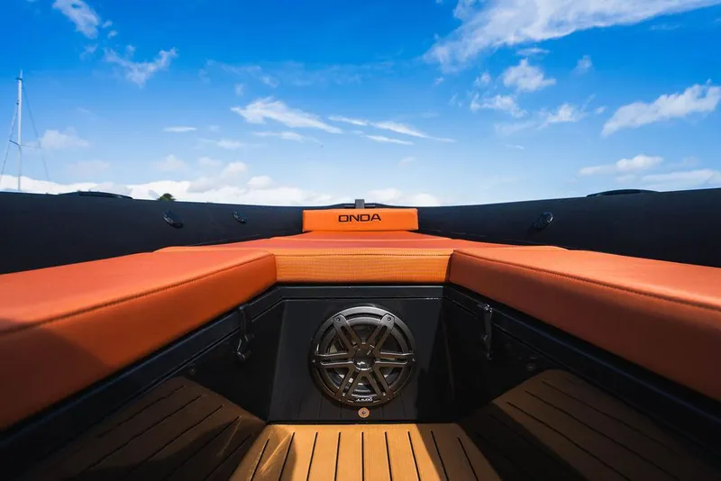 Slide: The Image of 2024 Onda Magna boat interior with orange seating and blue sky background. - 14