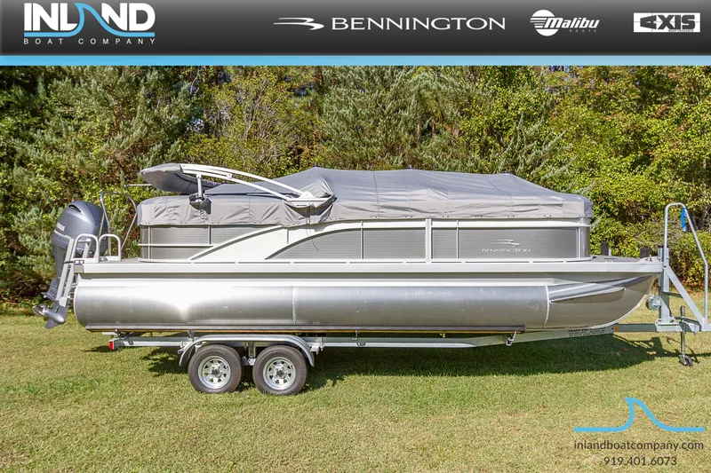Slide: The Image of 2023 Bennington 22 SXSR pontoon boat on a trailer, covered and parked on grass. - 21