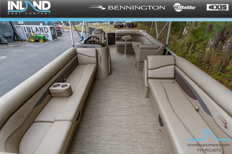 Slide: The Image of 2023 Bennington 22 SL pontoon boat interior with beige seating, cup holders, and steering console. - 6